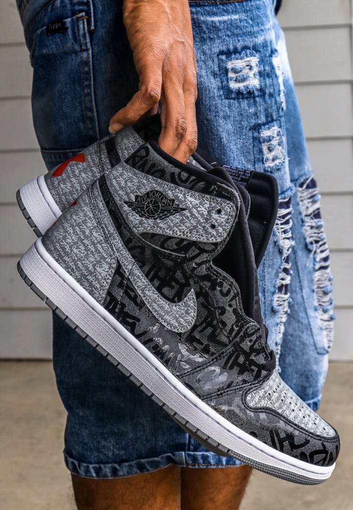 Close-up of trendy black and grey Nike sneakers being held, showcasing modern fashion style.